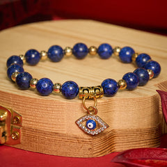 Lapis Lazuli Bracelet – Royal blue lapis with gold spacers on wood, burgundy background, evil eye charm