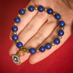 Lapis Lazuli Bracelet – Blue stone beads with crystal evil eye pendant on palm, red backdrop