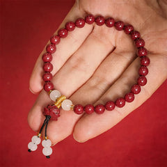 Cinnabar Lotus Enlightenment Bracelet – held in open palm showing wrist scale, speckled red beads with lotus pendant, mindfulness amulet
