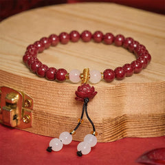Cinnabar Lotus Enlightenment Bracelet – angled view on wood cross-section with gold spacers and white jade beads, red background, beaded charm