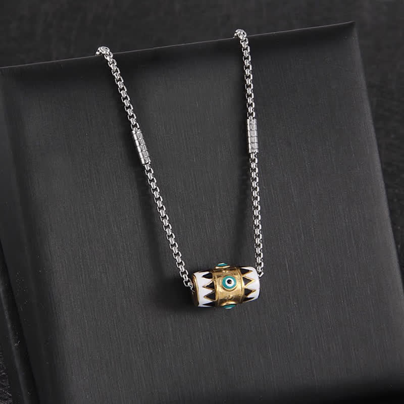 Evil Eye Pendant Necklace – Enamel evil eye cylinder with gold band on silver chain, black velvet background