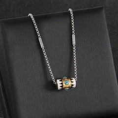 Evil Eye Pendant Necklace – Enamel evil eye cylinder with gold band on silver chain, black velvet background