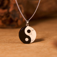 Yin Yang Obsidian Necklace - low angle of stone pendant on silver chain on wood, spiritual gift