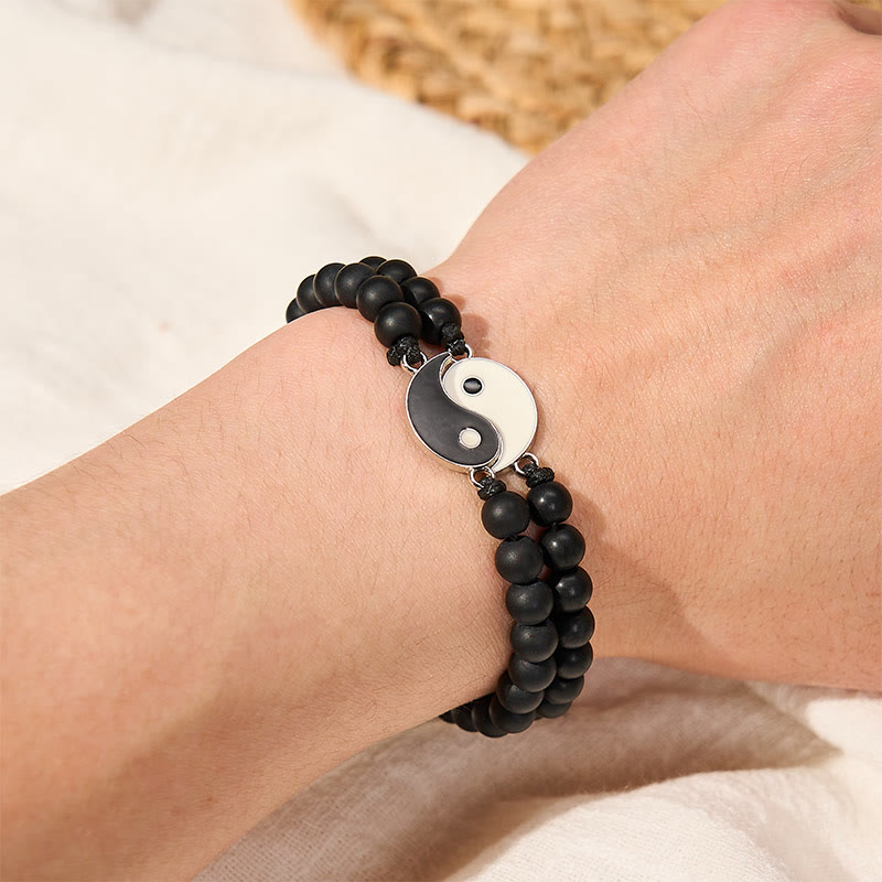 Hematite Lava Rock Yin Yang Bracelet - Lava stone bracelet with yin-yang medallion on dark stone surface