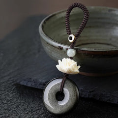 Rainbow Obsidian Lotus Peace Buckle Keychain - 45-degree view of lotus carving and silver flash obsidian, protection