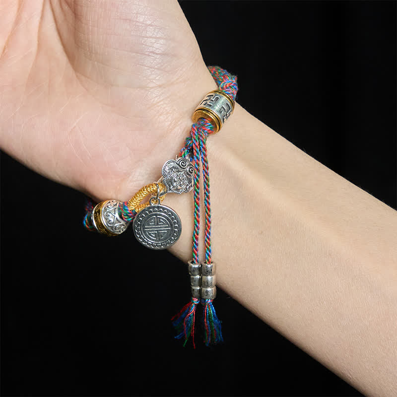 Fu Swastika Rope Bracelet - Braided cord bracelet with prayer wheel bead and silver longevity charm worn on wrist, Buddhist jewelry
