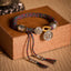 Fu Swastika Rope Bracelet - Multicolor braided cord with silver fortune Fu charm and metal beads on brown display box, handmade bracelet