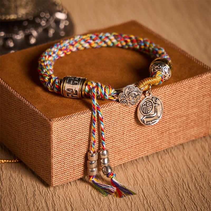 Fu Swastika Rope Bracelet - Colorful braided charm bracelet with Tibetan silver medallion and gold accents worn on wrist, bohemian ethnic jewelry