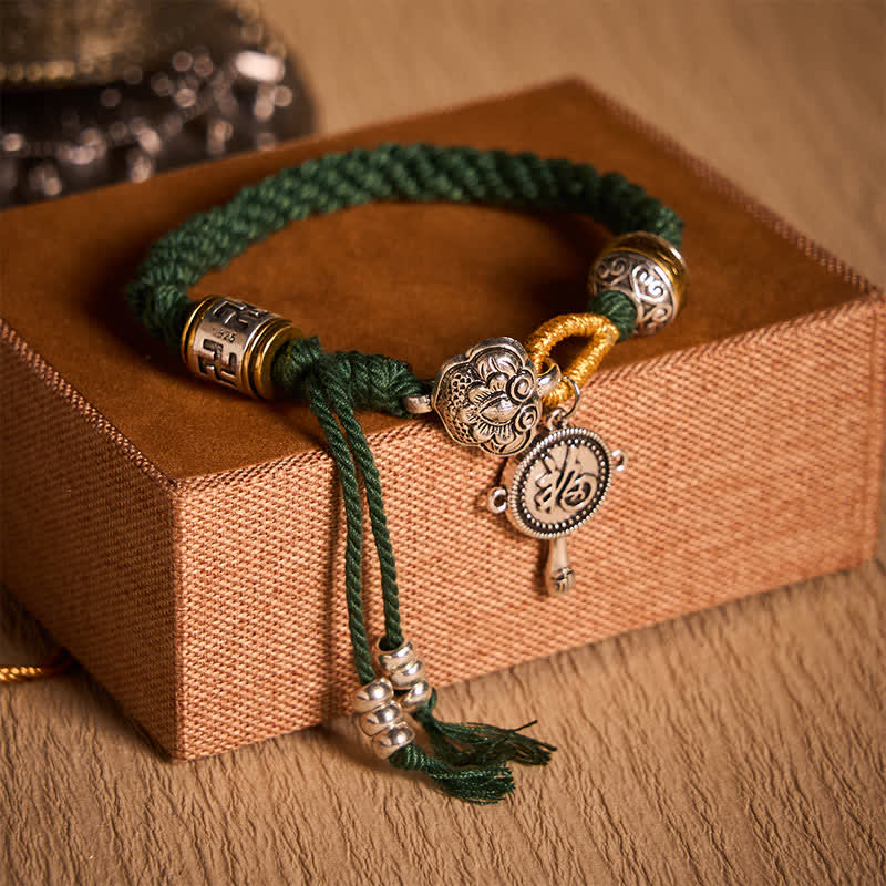 Fu Swastika Rope Bracelet - Green braided cord bracelet with silver floral charms and gold accents worn on wrist, Tibetan inspired jewelry