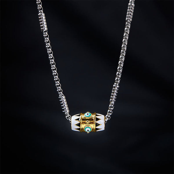 Evil Eye Pendant Necklace – Gold evil eye bead with black tribal pattern on silver chain, black backdrop