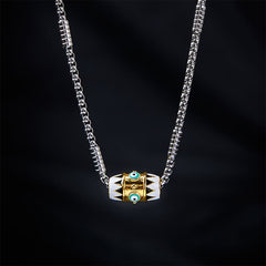 Evil Eye Pendant Necklace – Gold evil eye bead with black tribal pattern on silver chain, black backdrop