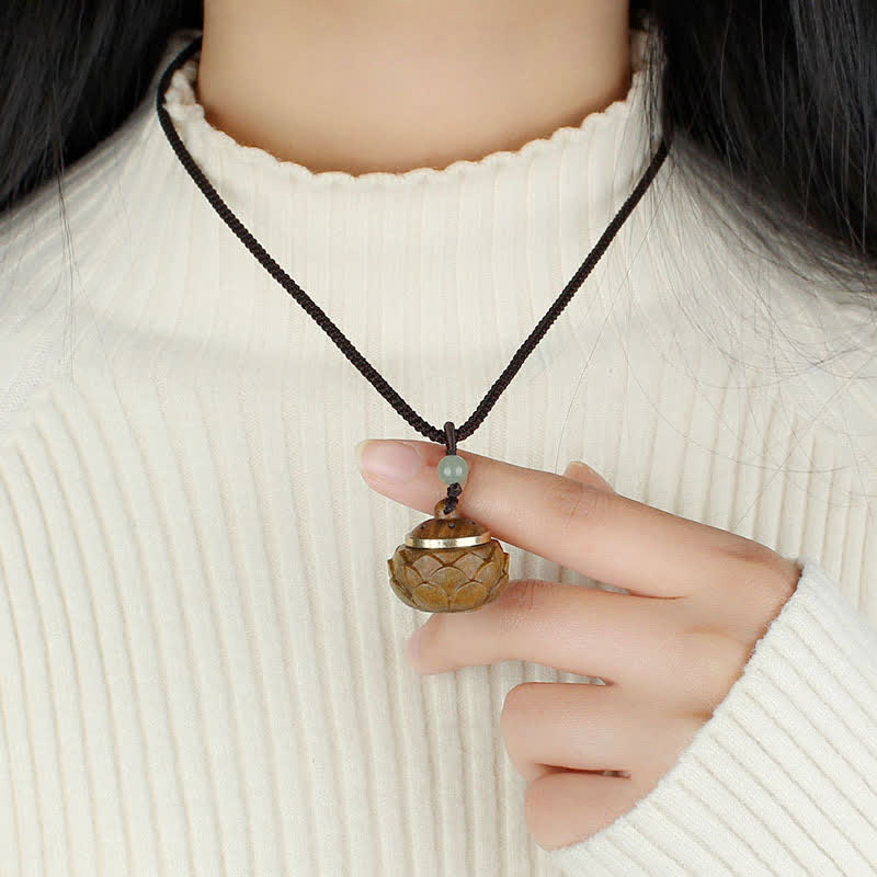 Om Mani Padme Hum Necklace – Spherical wooden lotus locket held in hand, gold band, jade bead on cream sweater