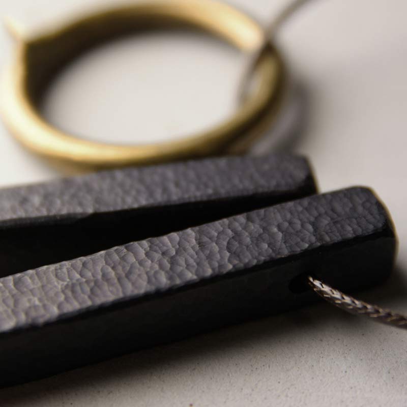 Zen Circle Ebony Wood Necklace - macro of hammered black bar texture, hand-forged surface detail