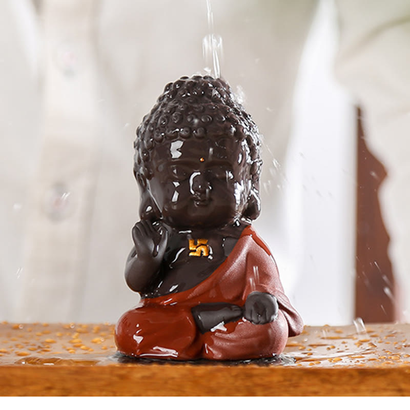 Small Buddha Purple Clay Decoration – tea pouring action shot, water streaming over figure revealing wet clay sheen, interact