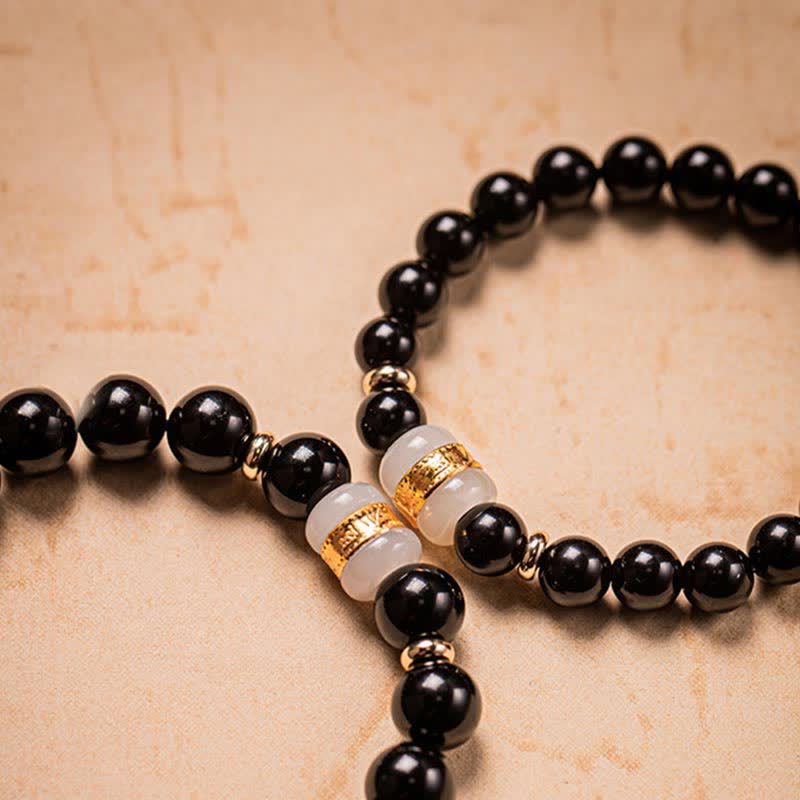 Black Obsidian Jade Bracelet – Matching pair flat lay on warm parchment showing gold-banded jade accents