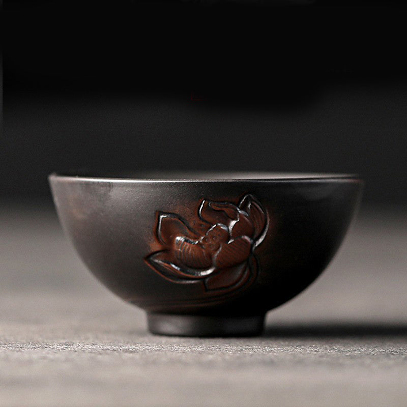 Ceramic Tea Cup – Single peony relief on dark body, shallow focus, wabi-sabi tea bowl