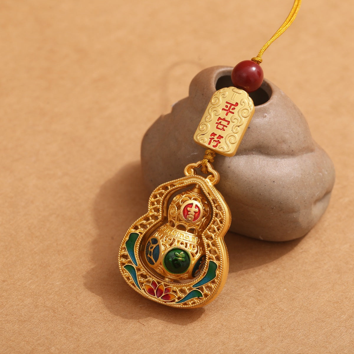 Gold rotating calabash keychain with green mantra bead and peace talisman, golden cord