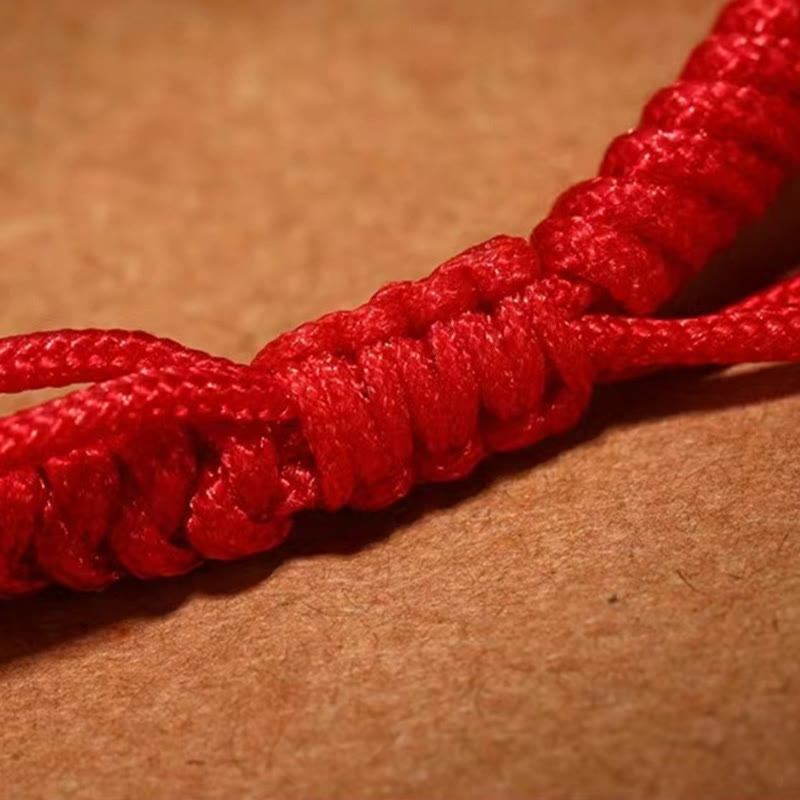 Tibetan Mantra Bracelet – Macro detail of red knotted cord texture on brown kraft paper, woven cord