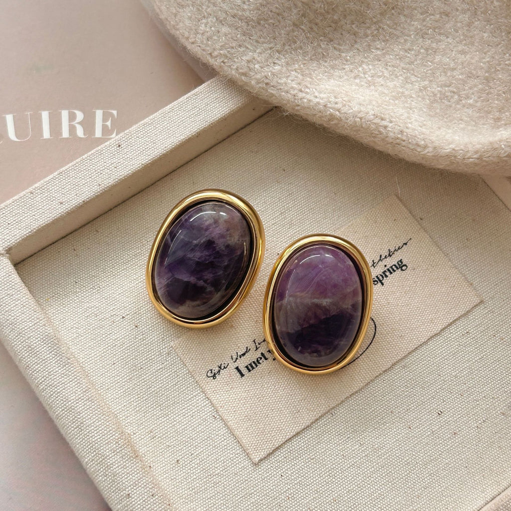 Amethyst Stud Earrings – purple amethyst oval studs in gold frames on beige canvas jewelry tray with knit fabric, bohemian earrings