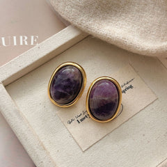 Amethyst Stud Earrings – purple amethyst oval studs in gold frames on beige canvas jewelry tray with knit fabric, bohemian earrings
