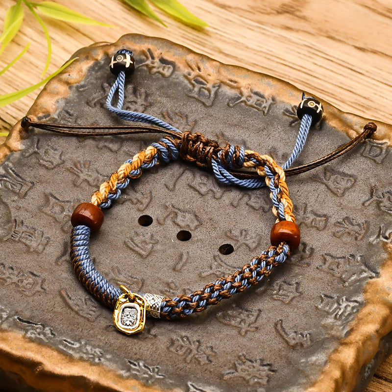 Tibetan Cord Bracelet – blue woven cord with wood beads and gold charm on carved stone, adjustable bracelet