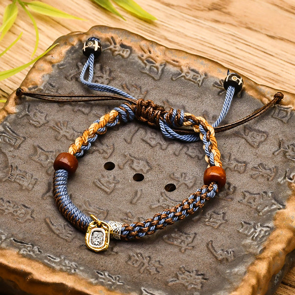 Tibetan Cord Bracelet – blue woven cord with wood beads and gold charm on carved stone, adjustable bracelet