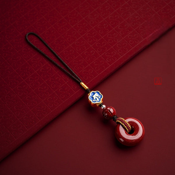 Natural cinnabar zodiac peace buckle amulet placed on traditional patterned red fabric