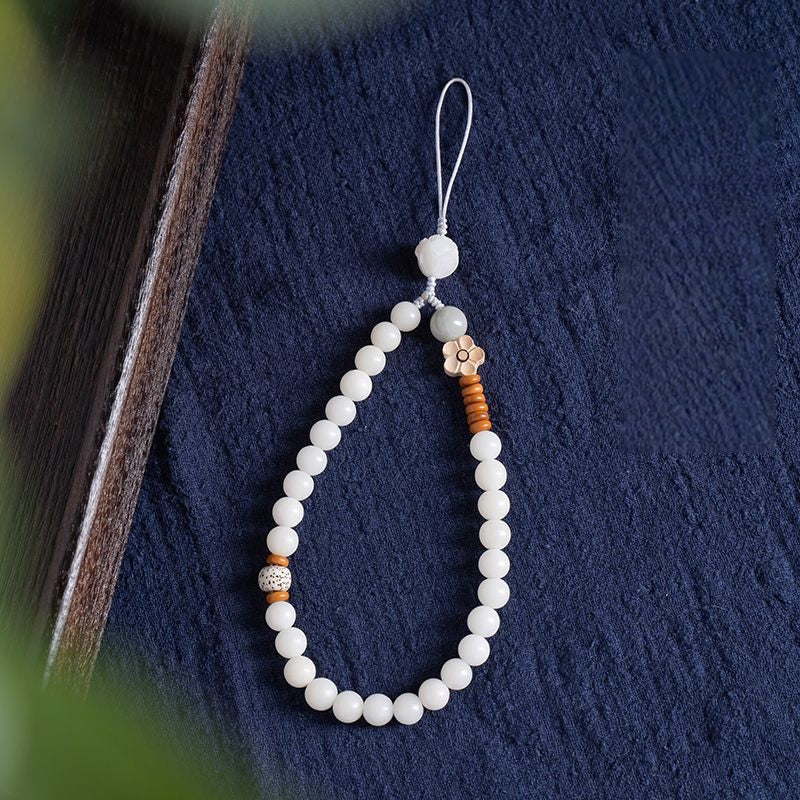White Jade Bodhi & Jadeite Crystal Phone Charm – White bodhi beads with green jadeite, clear crystals, and lotus carving on blue background