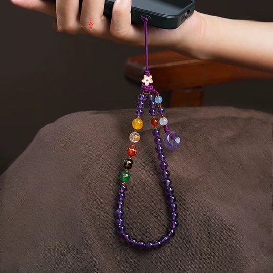Amethyst Phone Charm – purple bead strap attached to phone with multicolor wealth beads on brown