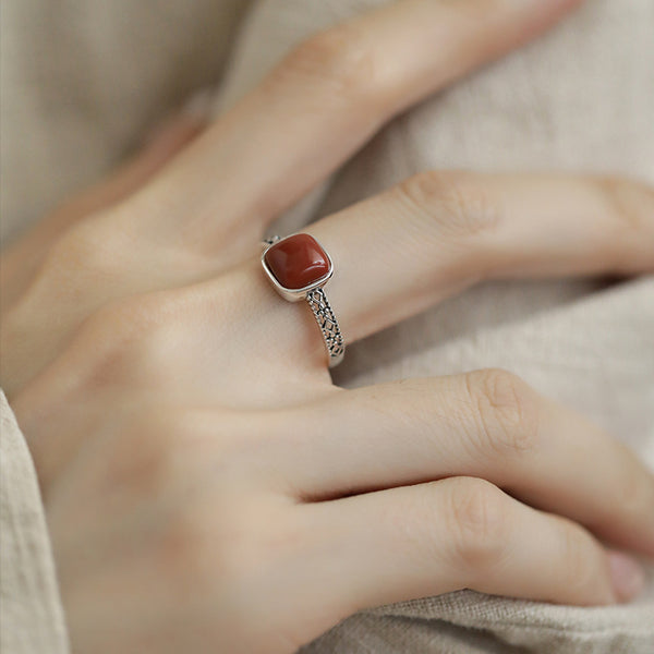 Red Agate Openwork Ring – worn on hand with light linen fabric showing intricate silver filigree band, grounding ring
