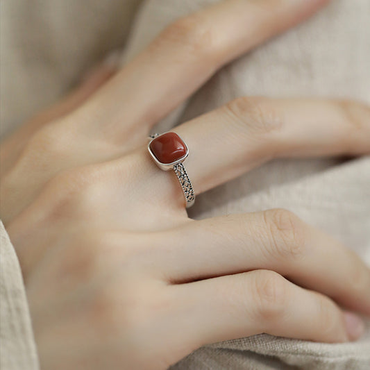 Red Agate Openwork Ring – worn on hand with light linen fabric showing intricate silver filigree band, grounding ring