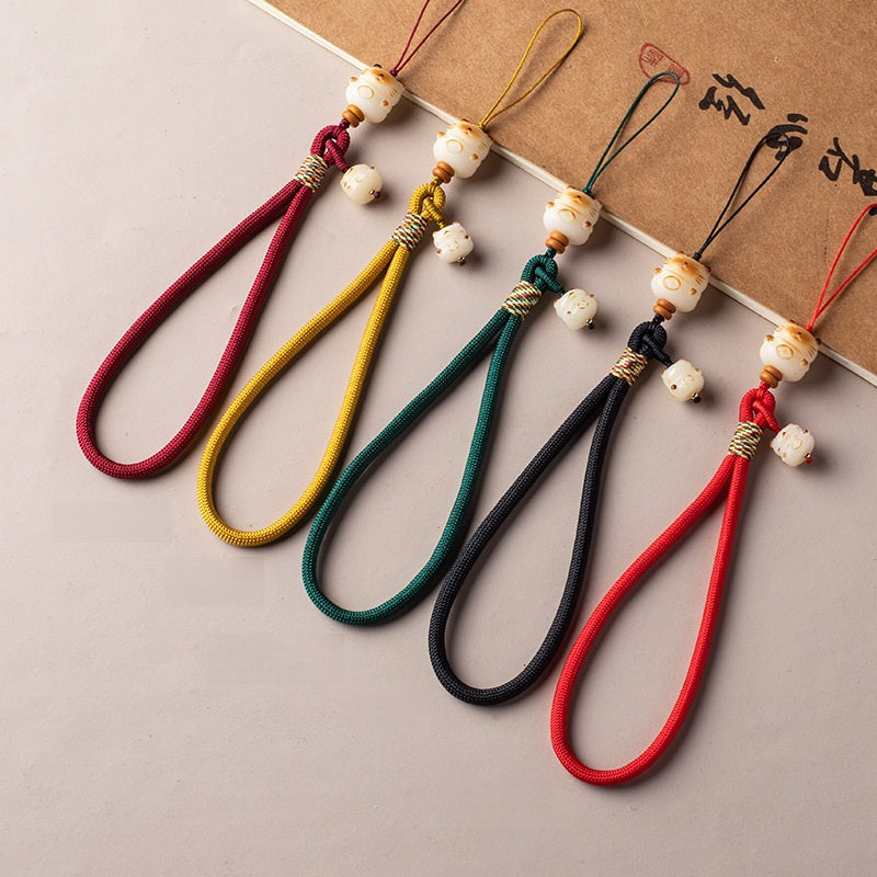 Five color variations of Bodhi Maneki Neko phone straps laid out together