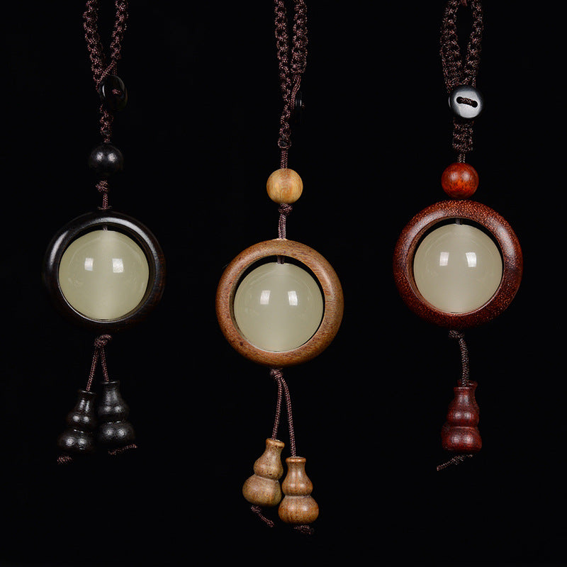 Feng Shui Sandalwood Keychain with Luminous Bead – Ebony black wood close-up on craft paper and blue fabric background