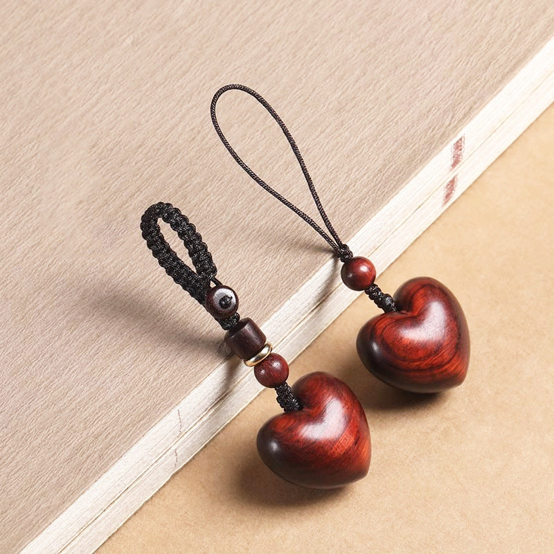 Rosewood Heart Keychain – pair of heart charms with mixed cords arranged diagonally on old book