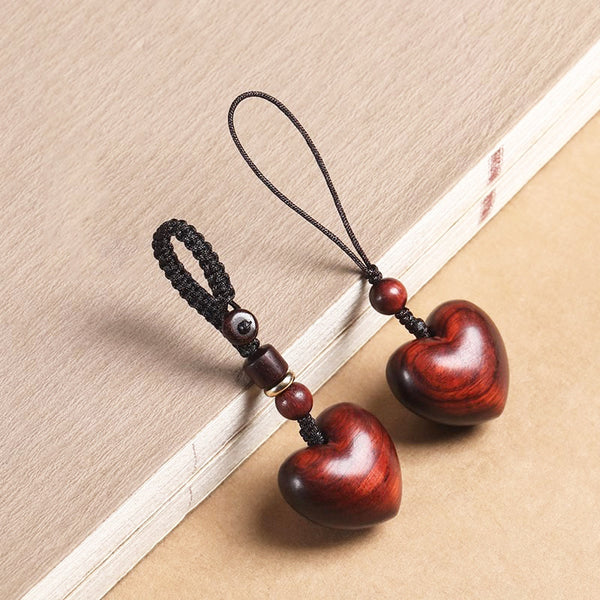 Rosewood Heart Keychain – pair of heart charms with mixed cords arranged diagonally on old book