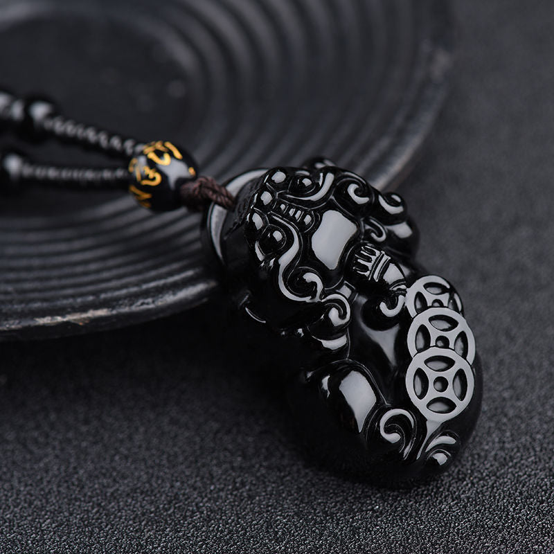 Obsidian Pixiu Necklace – Close-up of detailed pixiu carving on black ceramic plate, wealth symbol charm