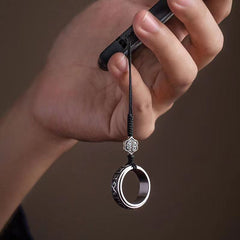 Mantra Phone Ring – hand holding smartphone with silver ring on finger, practical usage demonstration