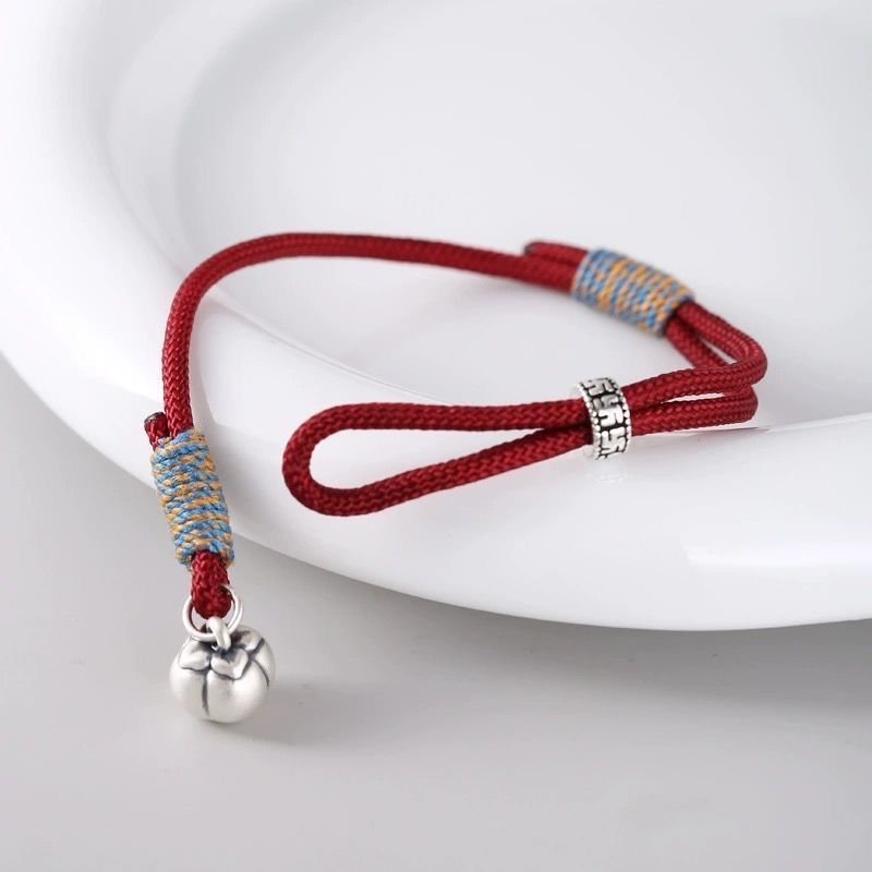 Persimmon Cord Bracelet – Red cord bracelet with silver charm on white ceramic dish, adjustable wish jewelry