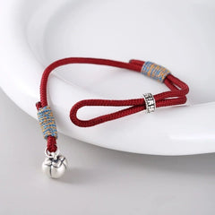 Persimmon Cord Bracelet – Red cord bracelet with silver charm on white ceramic dish, adjustable wish jewelry