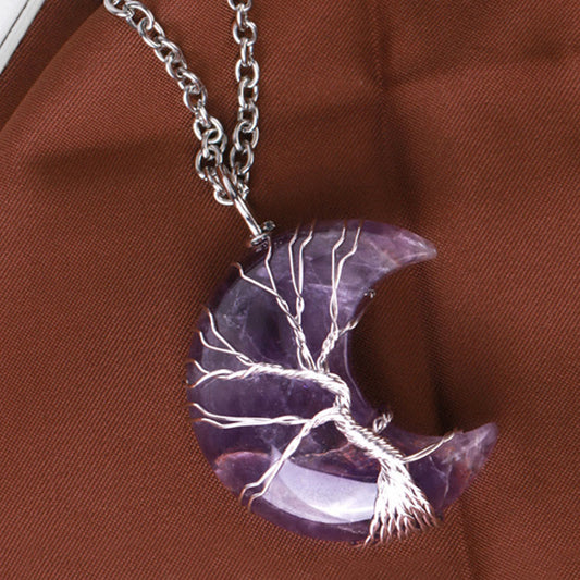 Quartz Crystal Moon Tree of Life Pendant – amethyst moon pendant on rust-brown fabric, three-quarter, crystal jewelry