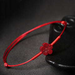 Cinnabar PiXiu Lotus Koi Fish Blessing Braid Bracelet – red flower bracelet draped on black ceramic vase, cinnabar protection accessory