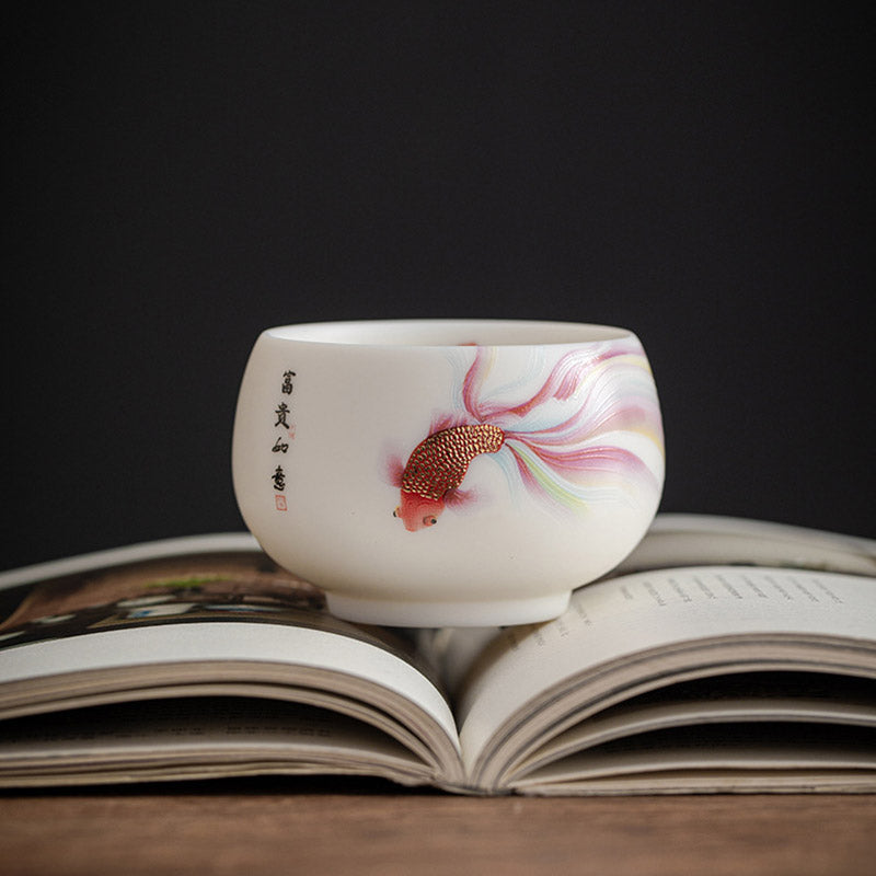 Koi Fish Porcelain Tea Cup - outdoor natural light shot with tea leaves nearby, tea culture