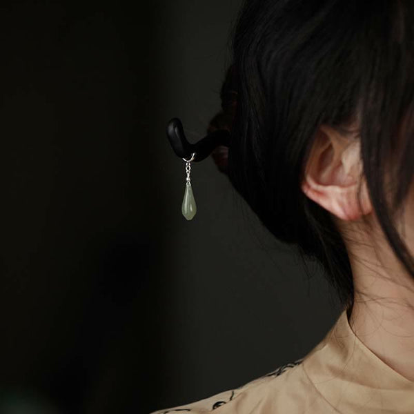 Side view of woman wearing ebony hairpin with jade teardrop pendant in her hair