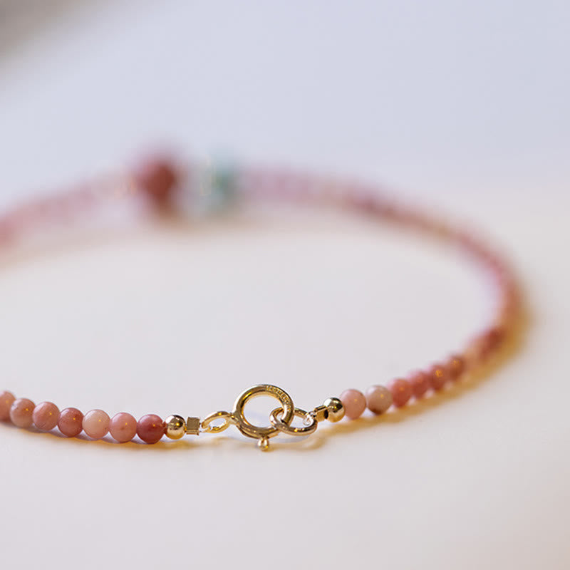 Rhodonite Loving Energy Bracelet – Pink stone beads with mauve focal and turquoise accent worn on wrist with beige knit sleeve, soft focus