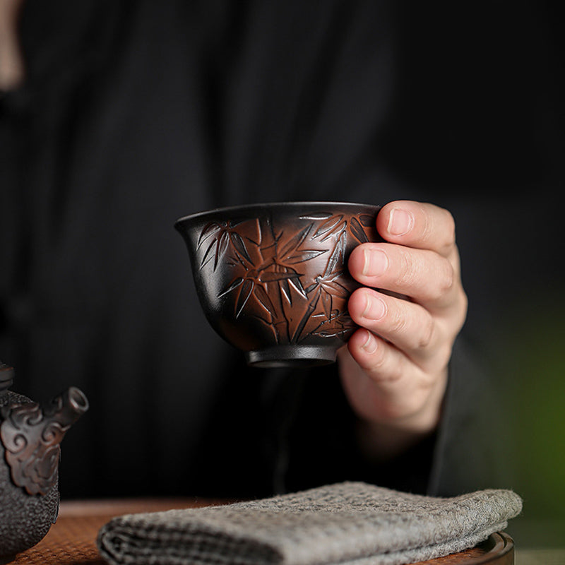 Ceramic Tea Cup – Hand holding bamboo carved cup beside teapot, gongfu tea ceremony