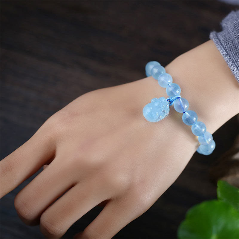 Aquamarine PiXiu Bracelet – Worn on wrist with blue PiXiu charm, grey sweater cuff, peace jewelry