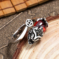 Feng Shui Garnet Pixiu Ring – angled side view with pixiu and coin on wood slice, bamboo mat background detail