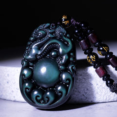 Tibetan Rainbow Obsidian PiXiu Necklace – close-up carved PiXiu with green iridescent sheen, black cord, feng shui wealth necklace