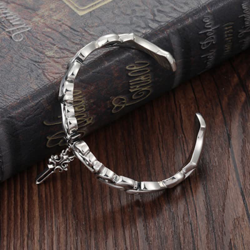 Men's twisted rope silver bracelet with gothic geometric links and decorative sword charm pendant on vintage book with Shakespeare text dark wood background