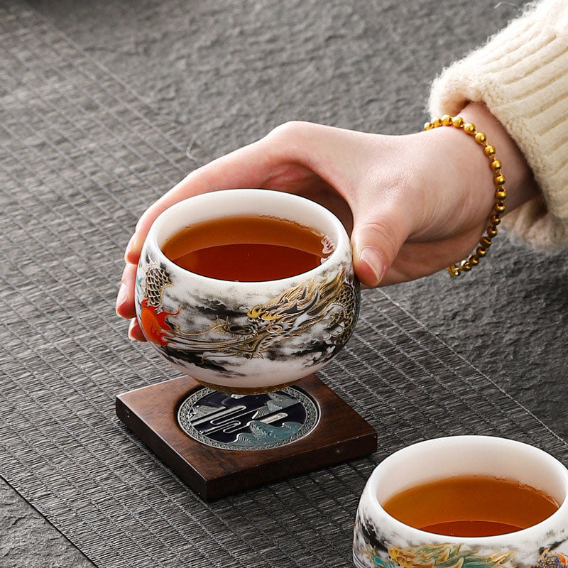 Dragon Playing Pearl Porcelain Teacup – Amber tea poured over dragon art, paired cups with teal, woven mat lifestyle